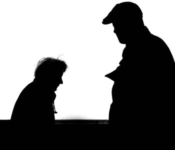 High contrast silhouette photo capturing two adults conversing against a white background.